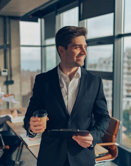 handsome-businessman-in-suit-standing-with-coffee-2025-03-26-13-47-03-utc (1)