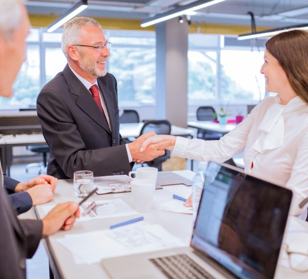 smiling-senior-man-shaking-hands-with-young-businesswoman-office (1)